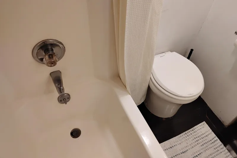 Slide: The Image of Bathroom with bathtub, shower curtain, and toilet on a 1977 Custom International Offshore 65. - 82