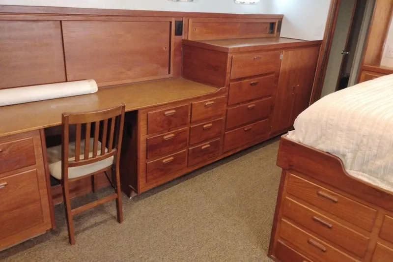 Slide: The Image of Wooden cabin interior with desk, drawers, and bed on a 1977 Custom International Offshore 65. - 84