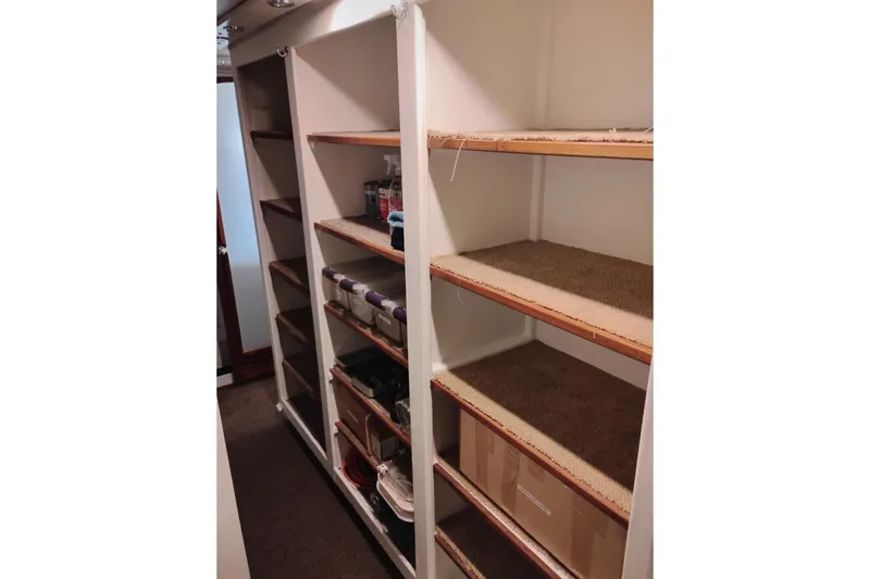 Slide: The Image of Storage shelves inside a 1977 Custom International Offshore 65 yacht, organized with various items. - 89