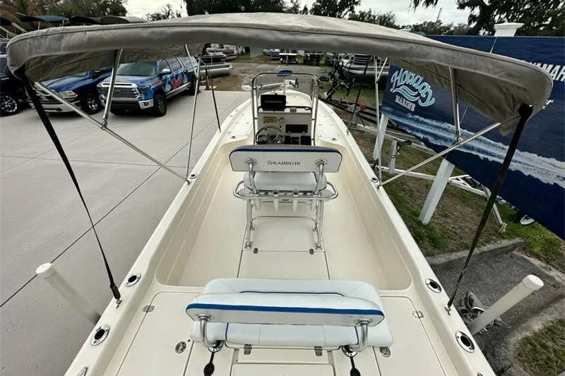 Slide: The Image of 2006 ShearWater 2400Z boat with canopy, parked outdoors, showcasing interior seating and controls. - 26