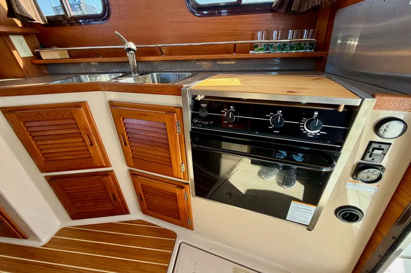 Slide: The Image of 2012 Ranger Tugs R-29 galley with wooden cabinets and stove. - 11