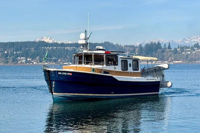 Slide: The Image of 2012 Ranger Tugs R-29 boat on serene lake with mountainous backdrop. - 2