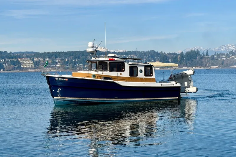 Slide: The Image of 2012 Ranger Tugs R-29 boat on calm water with scenic mountain backdrop. - 3