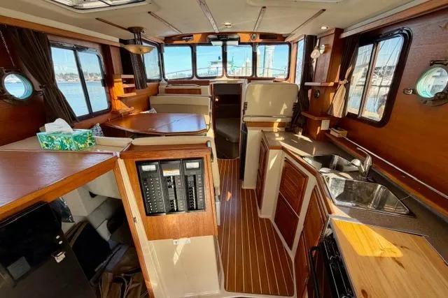 Slide: The Image of 2012 Ranger Tugs R-29 interior with wood finish, kitchen, and seating area. - 30
