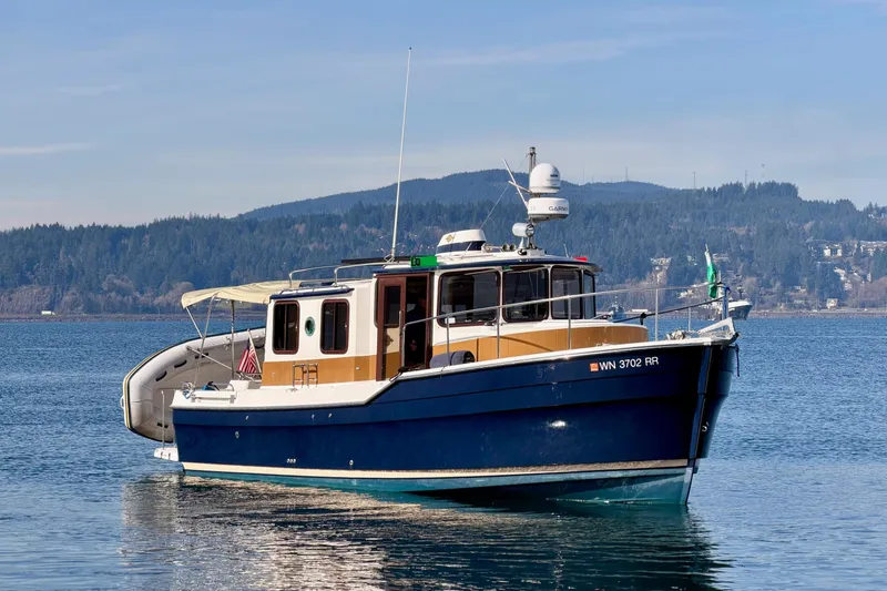 Slide: The Image of 2012 Ranger Tugs R-29 boat on calm water with scenic mountain backdrop. - 5