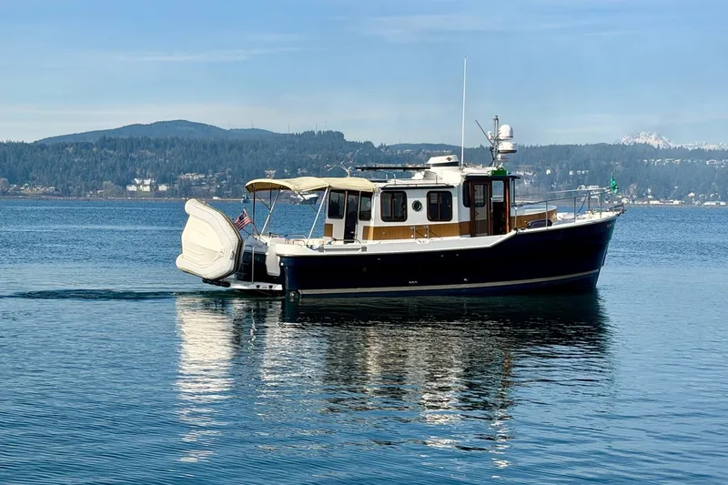Slide: The Image of 2012 Ranger Tugs R-29 boat on calm water with scenic mountain backdrop. - 7