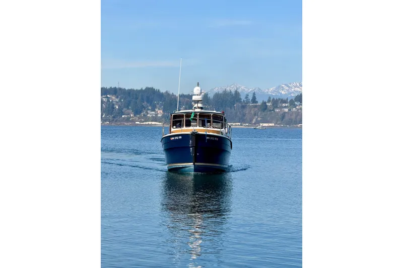Slide: The Image of 2012 Ranger Tugs R-29 boat cruising on a serene lake with mountainous backdrop. - 8