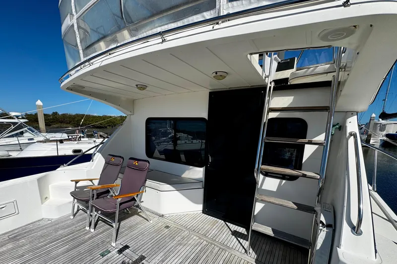 Slide: The Image of 1998 Mikelson 43 Sportfisher yacht deck with chairs and ladder under clear blue sky. - 3
