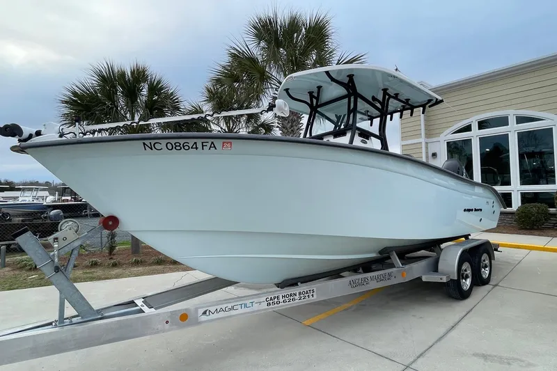 Slide: The Image of 2023 Cape Horn 24 XS boat on trailer, parked near palm trees and building. - 1