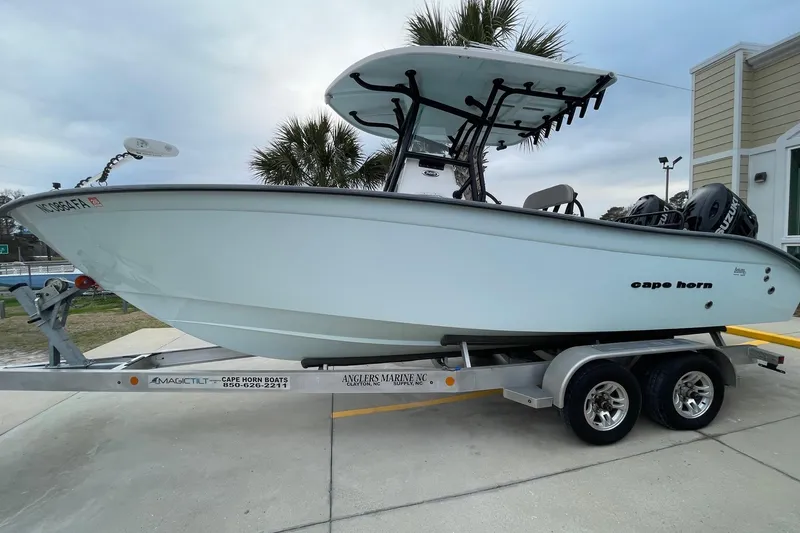 Slide: The Image of 2023 Cape Horn 24 XS boat on trailer, parked outdoors near palm trees. - 2