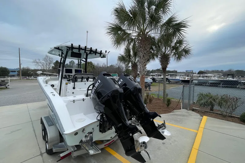 Slide: The Image of 2023 Cape Horn 24 XS boat with dual Suzuki engines, parked near palm trees. - 5