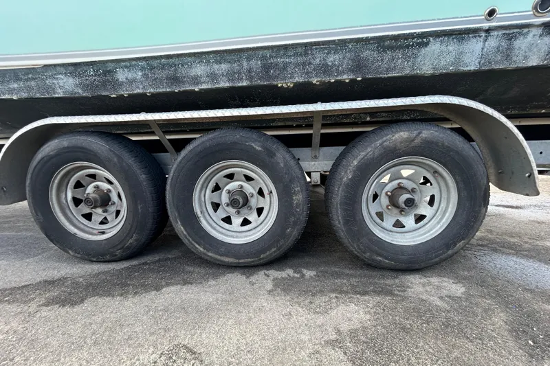 Slide: The Image of Triple-axle trailer for 2018 NauticStar 28 XS boat on wet pavement. - 102