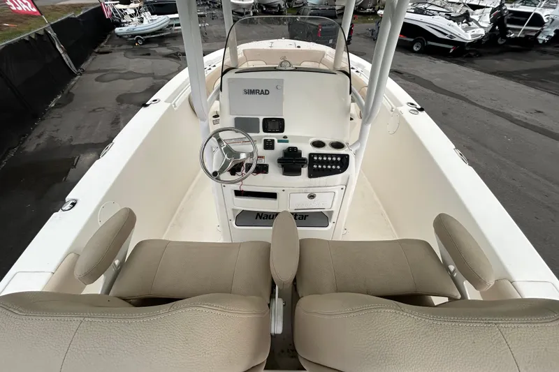 Slide: The Image of 2018 NauticStar 28 XS boat interior with seating and console, docked on pavement. - 12