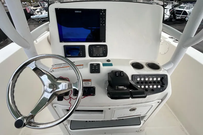 Slide: The Image of 2018 NauticStar 28 XS boat interior with rod holders, parked in a marina under blue skies. - 15