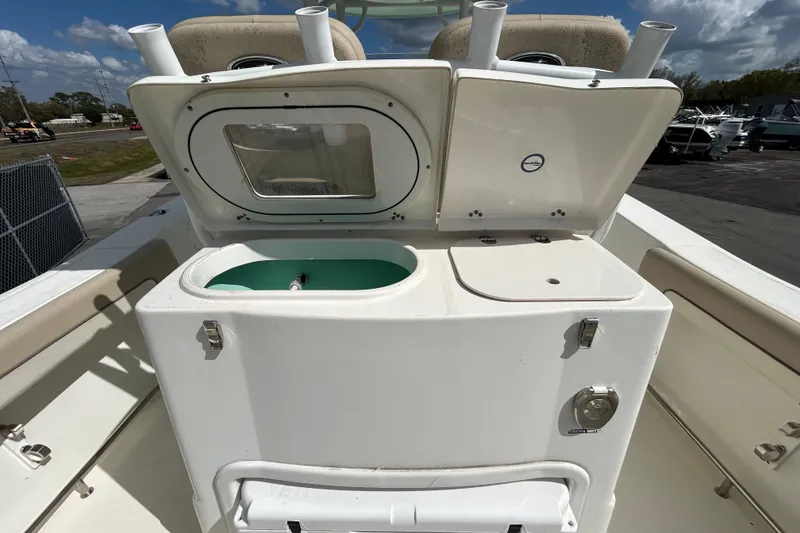 Slide: The Image of 2018 NauticStar 28 XS boat with open storage compartments and seating, under a partly cloudy sky. - 61