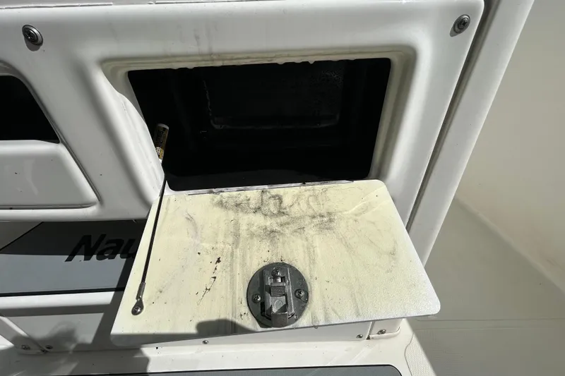 Slide: The Image of Open compartment on 2018 NauticStar 28 XS boat, showing storage area and latch. - 72