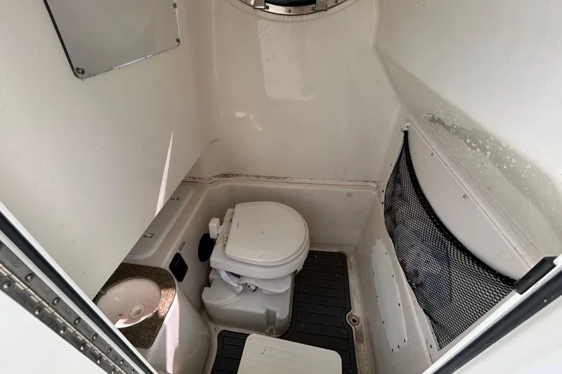 Slide: The Image of 2018 NauticStar 28 XS boat interior with compact marine toilet and storage net. - 82