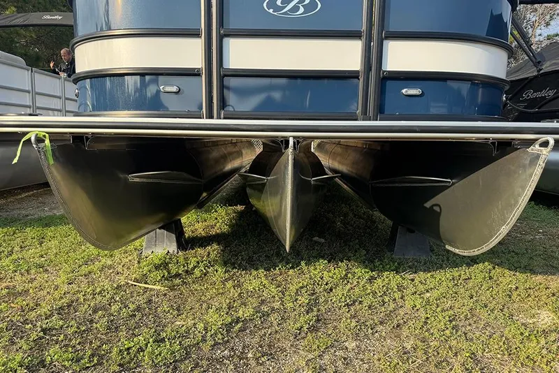 Slide: The Image of 2026 Bentley Pontoons Legacy 243 Swingback, close-up of pontoon hulls on grass. - 3
