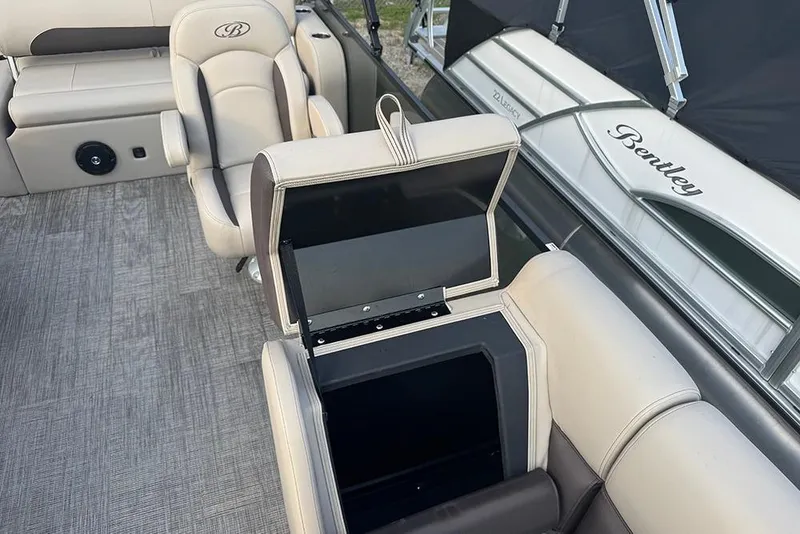 Slide: The Image of 2026 Bentley Pontoons Legacy 223 Swingback interior with open storage compartment and beige seating. - 16