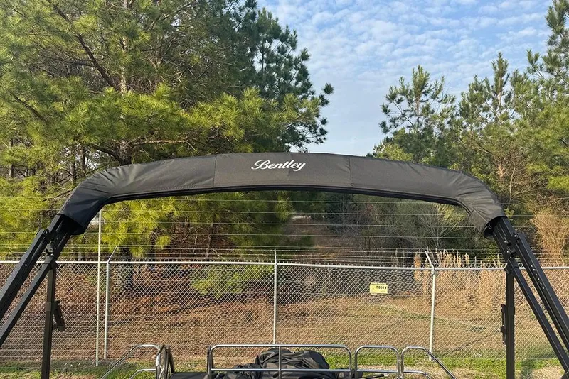 Slide: The Image of 2026 Bentley Pontoons Legacy 223 Swingback with canopy, surrounded by trees and fence. - 33