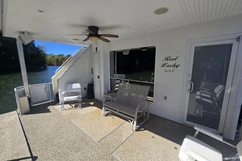 Slide: The Image of 2013 Thoroughbred 80'x 18' houseboat deck with seating, fan, and scenic lake view. - 17