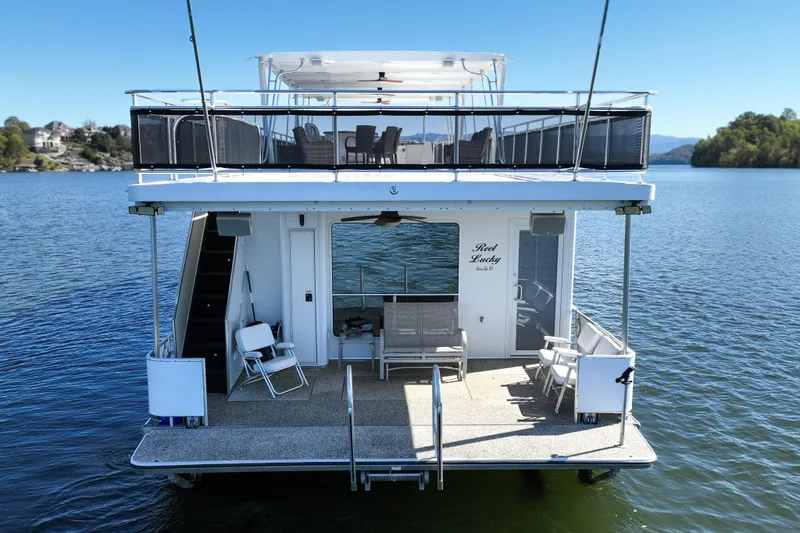 Slide: The Image of 2013 Thoroughbred houseboat on serene lake, featuring spacious deck and seating area. - 4