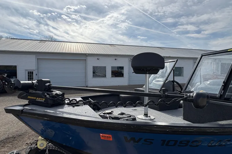Slide: The Image of 2017 Starcraft Renegade 168 DC boat with Minn Kota motor, parked near a white building. - 8
