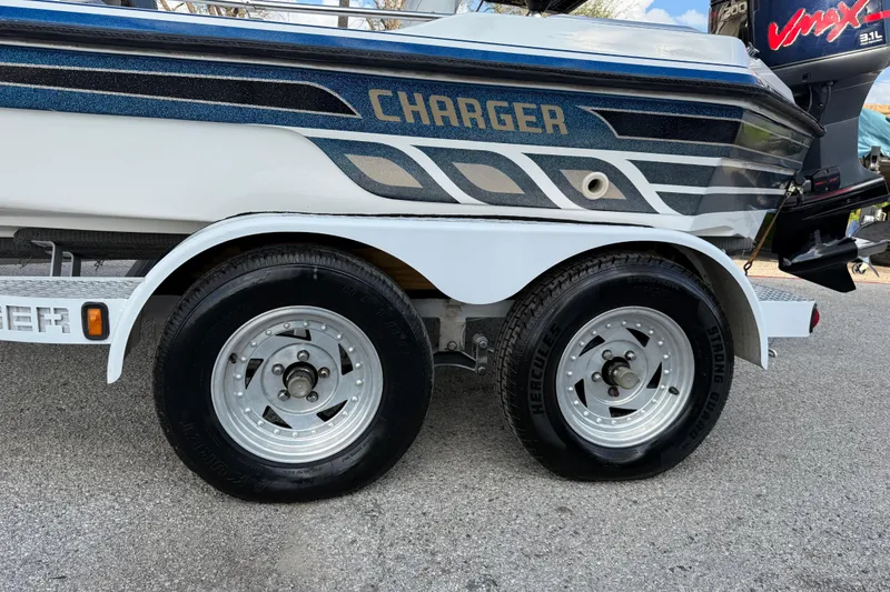Slide: The Image of Trailer of a 1999 Charger 195TF boat with dual wheels and stylish graphics. - 23
