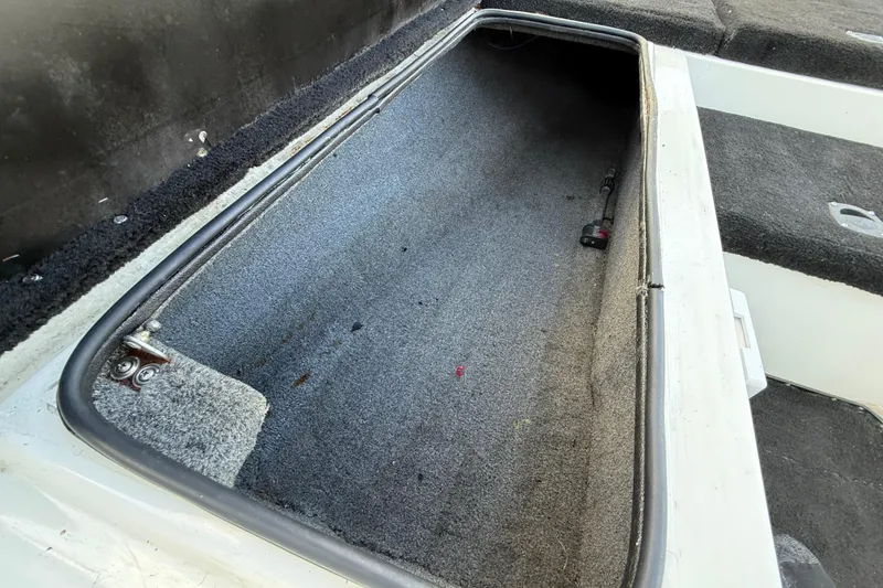 Slide: The Image of Open storage compartment in 1999 Charger 195TF boat, featuring carpeted interior. - 42