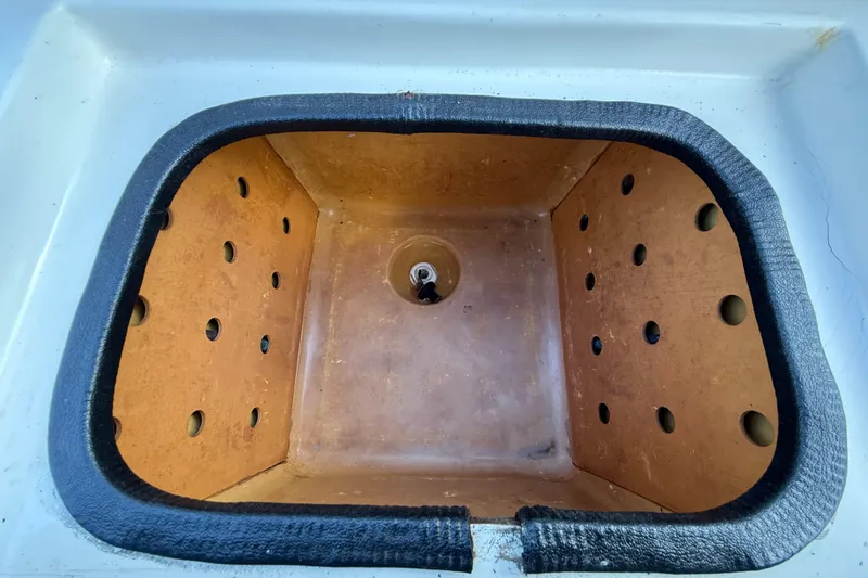 Slide: The Image of Livewell compartment in a 1999 Charger 195TF boat, featuring drainage holes and protective lining. - 50