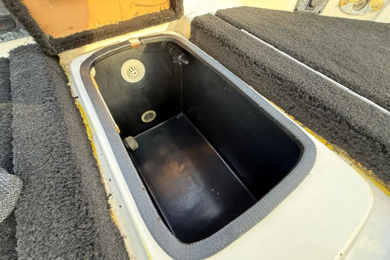 Slide: The Image of 1999 Charger 195TF boat storage compartment with carpeted edges and drainage system. - 52