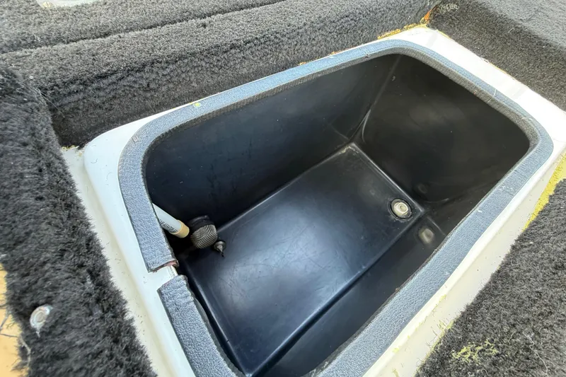Slide: The Image of 1999 Charger 195TF boat storage compartment with black interior and carpeted edges. - 53