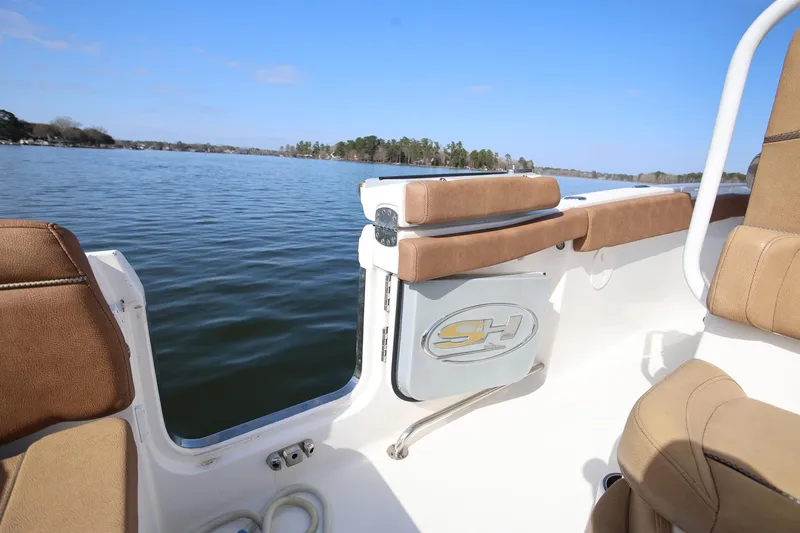 Slide: The Image of 2020 Sea Hunt Ultra 255 SE boat interior with tan seating on a calm lake. - 10