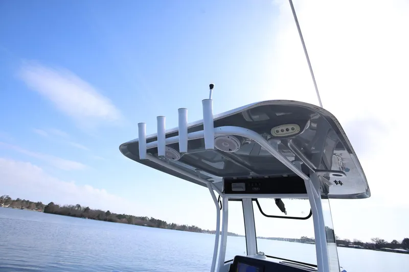 Slide: The Image of 2020 Sea Hunt Ultra 255 SE boat with T-top and rod holders on a calm lake. - 31