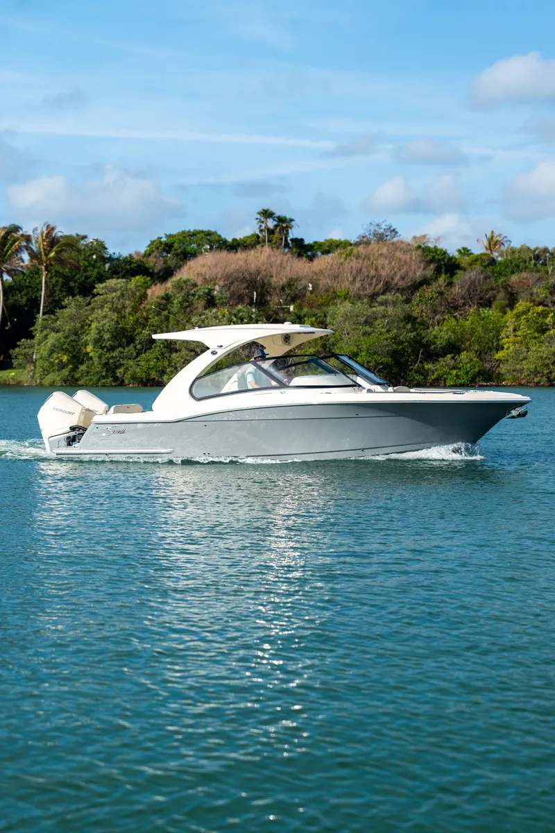 Slide: The Image of A 2027 Scout 288 Dorado cruising on calm waters, surrounded by lush greenery. - 9