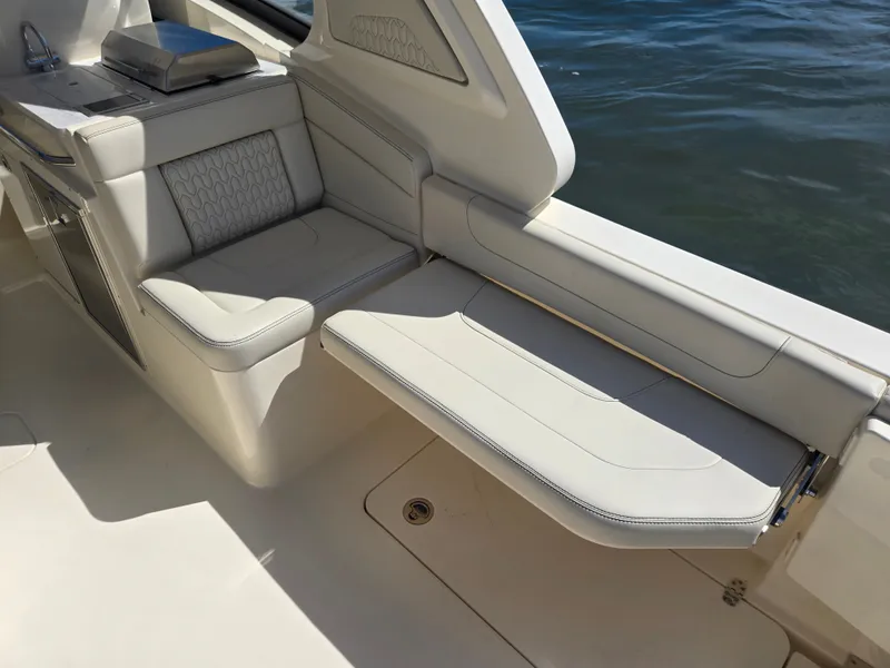 Slide: The Image of The 2027 Scout 288 Dorado features an elegant cream-colored bench seat with quilted pattern by the water. - 6