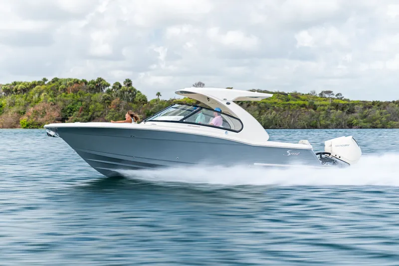 Slide: The Image of A Scout 288 Dorado boat speeds across the water, surrounded by lush greenery. - 10