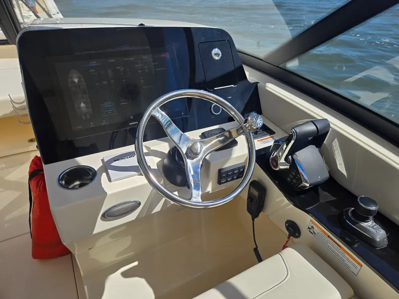Slide: The Image of The image shows the helm of a Scout 288 Dorado boat with a modern steering wheel and instruments. - 16