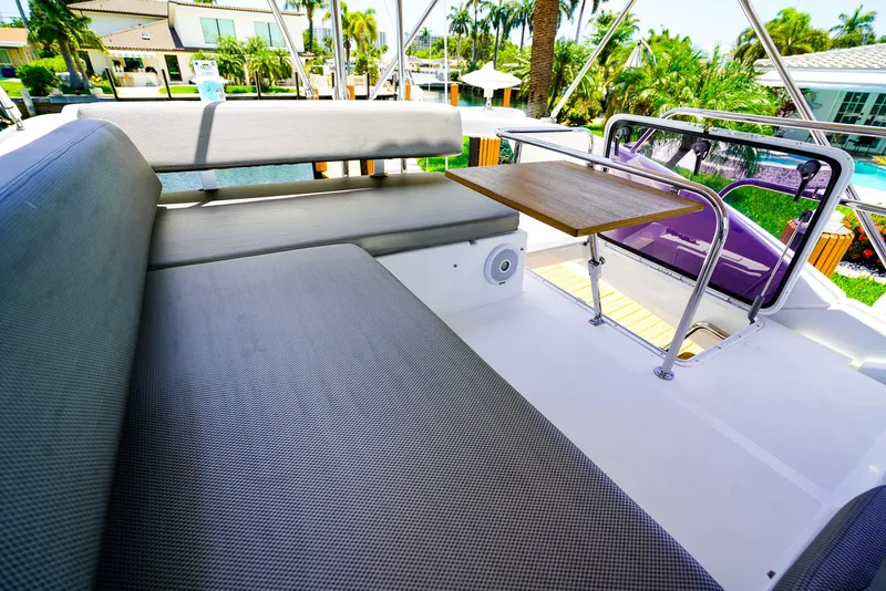 Slide: The Image of Azimut 42 Fly 2017 yacht flybridge with cushioned seating and table, surrounded by tropical scenery. - 17
