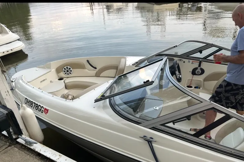 Slide: The Image of 2019 Stingray 208 LS boat docked, featuring sleek design and comfortable seating. - 23