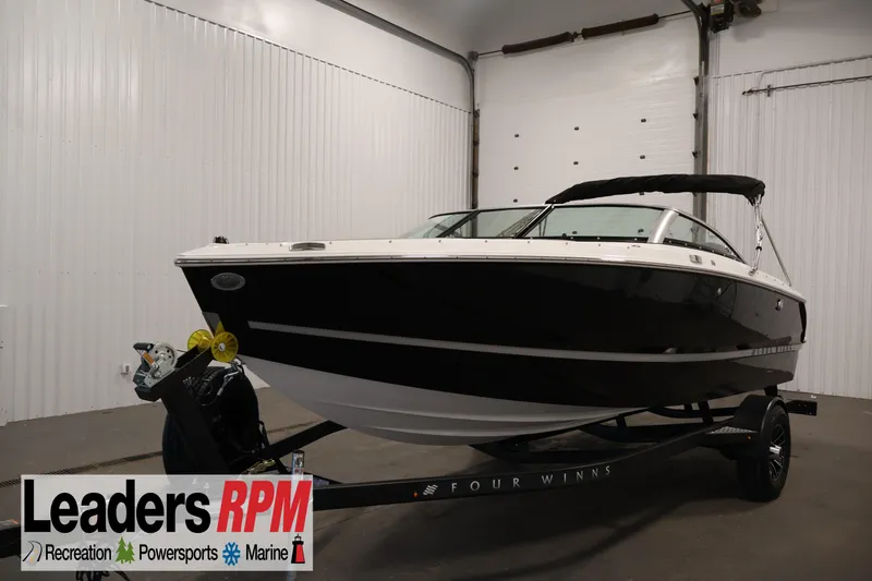 The Image of 2026 Four Winns H1 OB boat in showroom, black hull, on trailer, Leaders RPM logo visible. - 0