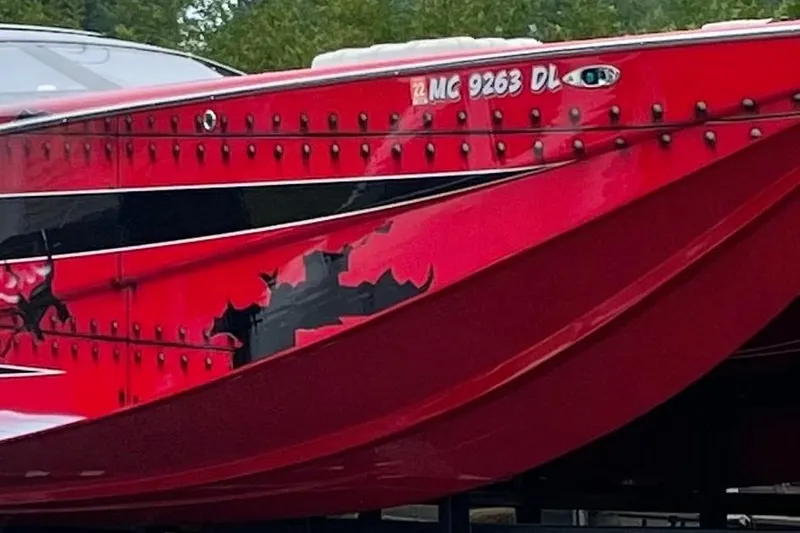Slide: The Image of Red 2007 Nor-Tech 4700 Super Cat boat with black accents and rivet details. - 4