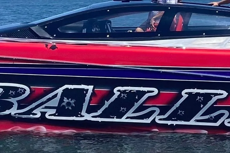 Slide: The Image of 2007 Nor-Tech 4700 Super Cat boat with vibrant red and black design on water. - 9