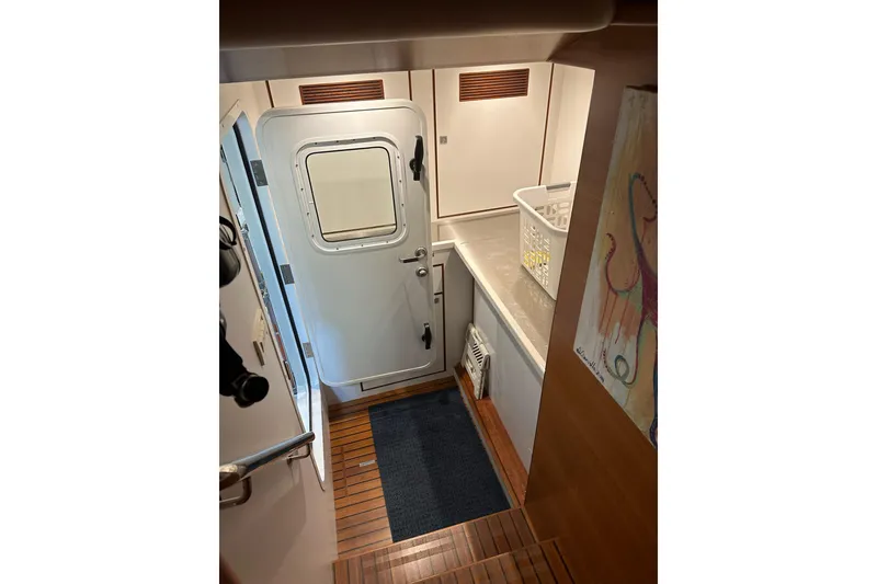 Slide: The Image of Interior of 2016 Nordhavn 60 yacht, featuring a door, wooden flooring, and a laundry basket. - 24