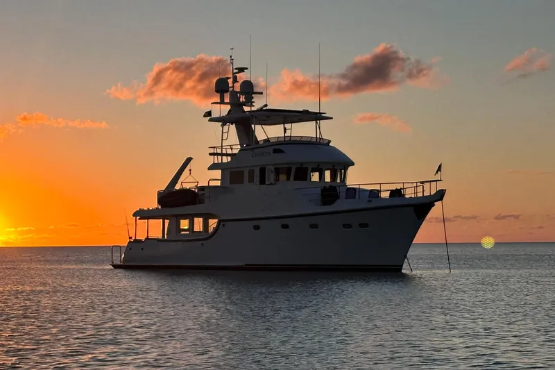 Slide: The Image of 2016 Nordhavn 60 yacht silhouetted against a vibrant sunset on calm waters. - 42