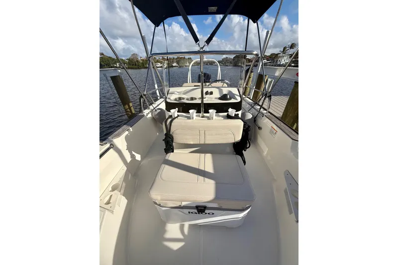 Slide: The Image of 2025 Boston Whaler 170 Montauk boat interior with seating and canopy, docked by the water. - 2