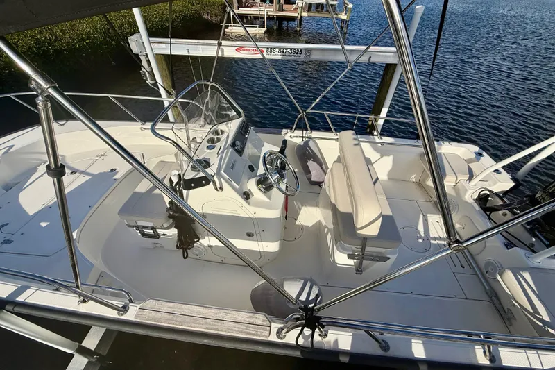 Slide: The Image of 2025 Boston Whaler 170 Montauk boat interior with steering console and seating, docked by the water. - 5