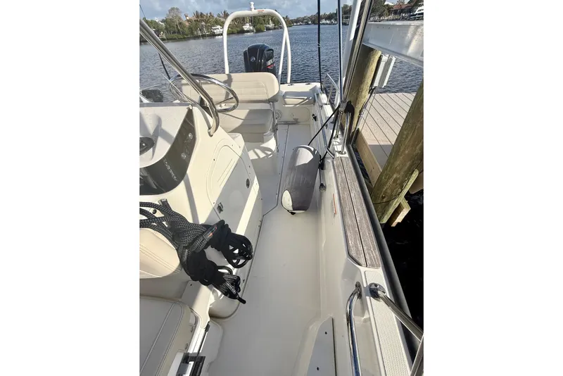 Slide: The Image of 2025 Boston Whaler 170 Montauk boat interior, docked by the water, showcasing seating and controls. - 7