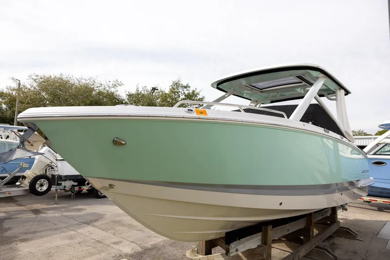 Slide: The Image of 2021 Chaparral 280 OSX boat in mint green, displayed on a stand outdoors. - 2