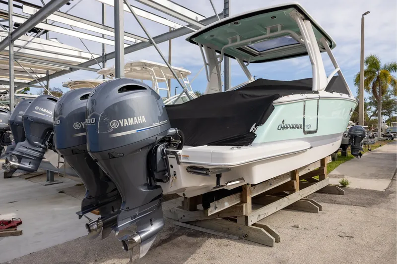 Slide: The Image of 2021 Chaparral 280 OSX boat with Yamaha engines, docked and covered, in a marina setting. - 4